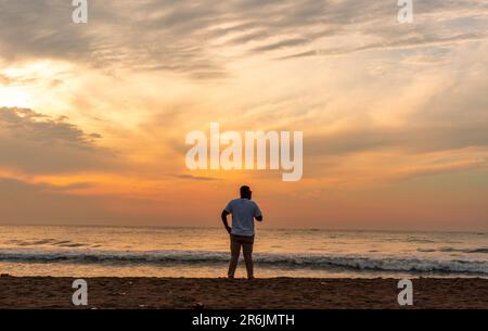 un homme regardant le lever du soleil Banque D'Images
