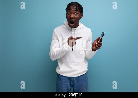 joyeux homme choqué jeune brunet homme américain communique dans le téléphone mobile Banque D'Images