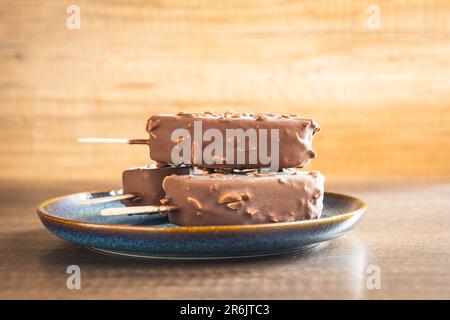 Popsicle, glace recouverte de chocolat sur la table en bois. Banque D'Images