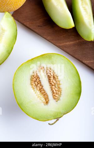 Demi-melon et tranches de melon sur planche à découper en bois. Vue de dessus. Banque D'Images