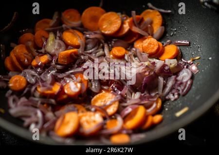 Les oignons et les carottes sont frits dans une poêle à frire profonde. Préparation de la cuisson. Banque D'Images