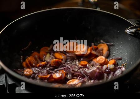 Les oignons et les carottes sont frits dans une poêle à frire profonde. Préparation de la cuisson. Banque D'Images