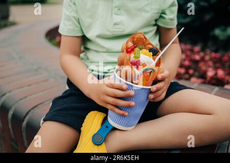 Les enfants se font les mains avec de délicieuses gaufres et bonbons sucrés, de la crème et de la confiture Banque D'Images