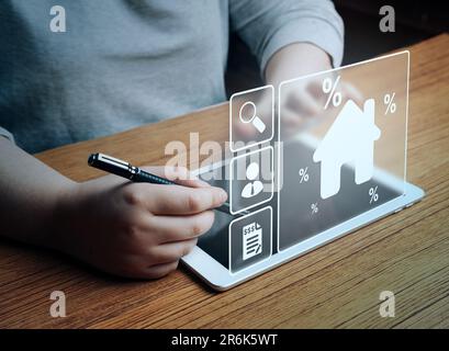 Une femme utilise une tablette numérique pour rechercher une nouvelle maison. Acheter un concept de maison. Immobilier. Emplacement, efficacité énergétique et valeur de propriété. Écran virtuel. Banque D'Images