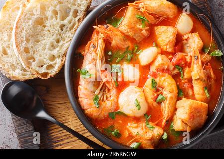 Fruits de mer et ragoût de poisson tels que crevettes, moules, pétoncles, calmar avec tomates dans un bol sur la table. Vue horizontale du dessus Banque D'Images