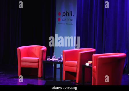 Cologne, Allemagne. 09th juin 2023. Trois fauteuils et boissons rouges sur une petite table se dressent devant une bannière avec le logo et l'inscription phil.cologne internationales Philoshiefest sur le podium du festival international de philosophie Phil.Cologne. Credit: Horst Galuschka/dpa/Alay Live News Banque D'Images