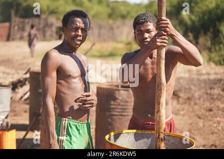 Andanovory, Madagascar - 30 avril 2019: Deux hommes malgaches inconnus qui extraient du jus de fruits dans un grand baril avec un poteau en bois - c'est à utiliser Banque D'Images
