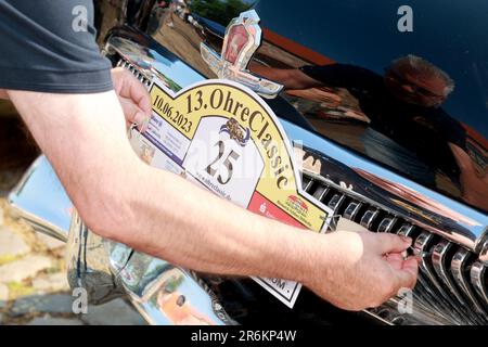 Wolmirstedt, Allemagne. 10th juin 2023. Une plaque de démarrage pour le modèle 13th Ohre Classic est fixée à une voiture classique. 110 participants prennent part à la rencontre voiture classique avec leur voiture. Depuis le point de départ du domaine du château de Wolmirstedt, les amateurs de voitures classiques traversent cette année le nord de Saxe-Anhalt. Credit: Peter Gercke/dpa/Alay Live News Banque D'Images