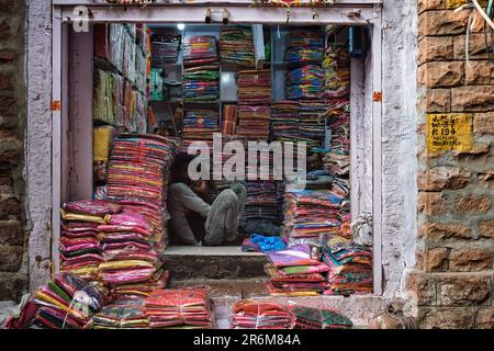 Fournisseur de vêtements en tissu montrant de nouveaux échantillons aux femmes locales dans le marché de Sadar. Jodhpur, Rajasthan, Inde Banque D'Images