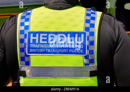 Cardiff, pays de Galles - juin 2023 : vue rapprochée du panneau bilingue sur le gilet d'un officier de la police britannique des transports en patrouille Banque D'Images