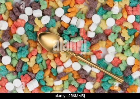 Cuillère dorée sur fond de cornflakes colorés au-dessus de la vue de dessus Banque D'Images