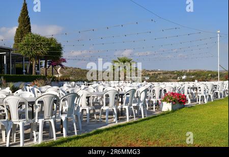 Café extérieur avec tables en plastique blanc et chaises Banque D'Images