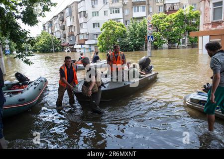 Les agents de sauvetage et les bénévoles tirent les bateaux sur terre tout en effectuant des opérations de recherche et de sauvetage dans les eaux de Kherson. Les efforts de sauvetage, d'évacuation et d'aide se sont poursuivis pendant une troisième journée à Kherson, en Ukraine, après que la destruction du barrage de Kakhovka ait causé des inondations catastrophiques le long de la rivière Dnipro, près des villages environnants de Kherson, sur les deux rives de la rivière. Les forces russes ont commencé à bombarder les lieux d'évacuation et de secours en blessant des volontaires et des policiers. Banque D'Images