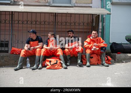 Les secouristes prennent une pause dans les eaux de crue pour manger un snack près d'un quartier inondé à Kherson, en Ukraine, le troisième jour de fortes inondations dans tout Kherson. Les efforts de sauvetage, d'évacuation et d'aide se sont poursuivis pendant une troisième journée à Kherson, en Ukraine, après que la destruction du barrage de Kakhovka ait causé des inondations catastrophiques le long de la rivière Dnipro, près des villages environnants de Kherson, sur les deux rives de la rivière. Les forces russes ont commencé à bombarder les lieux d'évacuation et de secours en blessant des volontaires et des policiers. Banque D'Images