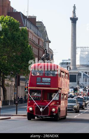 Mariage Party voyageant dans un bus Routemaster londonien d'époque en voiture à Whitehall, Westminster, Londres, Royaume-Uni, avec Nelson's Column derrière Banque D'Images