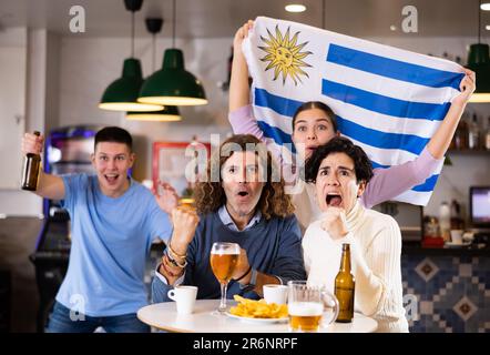 Les fans du drapeau de l'Uruguay célèbrent la victoire de leur équipe préférée au bar à bière Banque D'Images