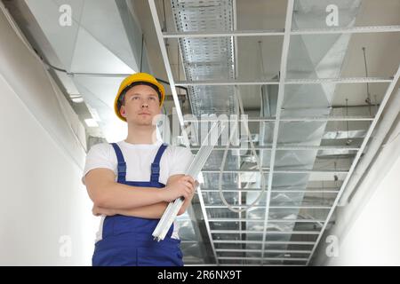 Travailleur avec profil métallique à l'intérieur. Installation au plafond suspendu Banque D'Images