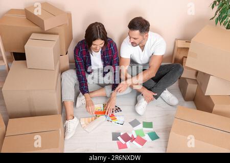 Un couple heureux entouré de boîtes mobiles en choisissant les couleurs dans le nouvel appartement, au-dessus de la vue Banque D'Images