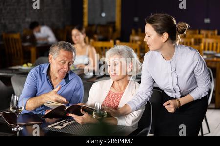 Femme serveur prenant la commande d'un couple âgé au restaurant Banque D'Images