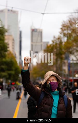 MELBOURNE, AUSTRALIE - JUIN 06 : une femme portant un masque avec son poing dans les airs traverse le CBD lors d'un rassemblement Black Lives Mater le 06 juin 2020 à Melbourne, en Australie. Cet événement a été organisé pour se rassembler contre les décès d'autochtones en détention en Australie, ainsi que dans le cadre de manifestations à travers les États-Unis à la suite du meurtre d'un homme noir non armé George Floyd aux mains d'un agent de police à Minneapolis, dans le Minnesota. Banque D'Images