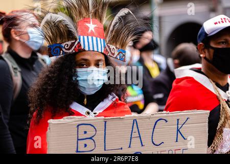 MELBOURNE, AUSTRALIE - 06 JUIN : une femme portant un casque Mauri Tribal et un masque facial tient un écriteau alors qu'elle marche dans le quartier des affaires lors d'un rassemblement Black Lives Mater le 06 juin 2020 à Melbourne, en Australie. Cet événement a été organisé pour se rassembler contre les décès d'autochtones en détention en Australie, ainsi que dans le cadre de manifestations à travers les États-Unis à la suite du meurtre d'un homme noir non armé George Floyd aux mains d'un agent de police à Minneapolis, dans le Minnesota. Banque D'Images