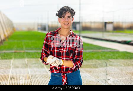 Portrait d'une femme jardinière positive dans une maison de hothouse Banque D'Images