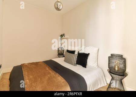 une chambre avec des murs blancs et du parquet la chambre est décorée dans des tons neutres, y compris des touches de noir et d'or Banque D'Images