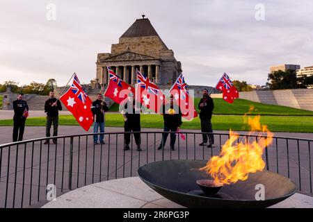 MELBOURNE, AUSTRALIE - 25 AVRIL : des membres du Conseil souverain australien tiennent l'Ensign rouge australien devant le Temple du souvenir avec la flamme éternelle en premier plan peu après le service de l'aube pendant le COVID 19 le jour ANZAC 25 avril 2020 à Melbourne, en Australie. Banque D'Images