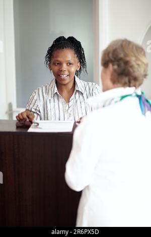 Réceptionniste de l'hôtel, hospitalité et une femme noire aidant un touriste senior à s'enregistrer dans un complexe de luxe. Concierge, voyage ou escapade avec un Banque D'Images