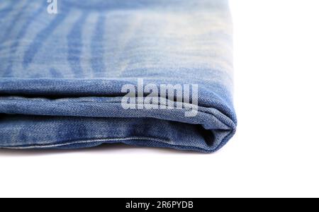 Un Jean bleu plié sur le fond blanc gros plan Banque D'Images