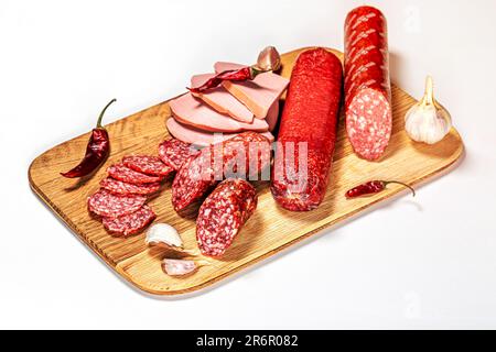 Une planche à découper présentant une variété d'aliments, y compris plusieurs tranches de saucisse, des haricots de saucisse et des herbes Banque D'Images