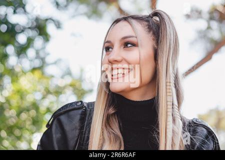 Une magnifique jeune femme aux cheveux blonds et tressés est capturée à l'extérieur par une journée ensoleillée. La photo présente une faible profondeur de champ, avec un effet de flou Banque D'Images