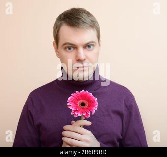 Jeune homme tenir gerbera flower dans la main. Banque D'Images