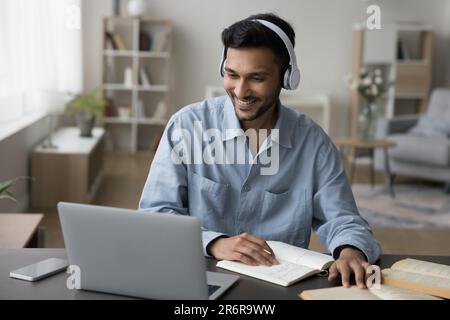 Joyeux jeune étudiant indien gars dans le casque regarder la vidéo d'apprentissage Banque D'Images