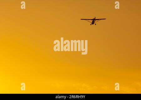 Silhouette d'avion ultra-légère dans un ciel orange au coucher du soleil Banque D'Images