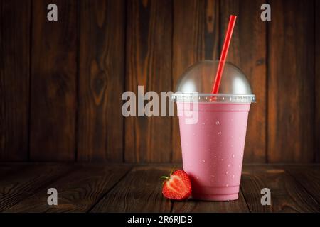 milkshake à la fraise dans du verre plastique jetable avec de la paille sur la table Banque D'Images