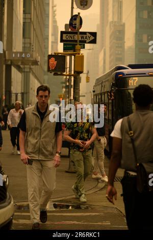 Les piétons dehors pendant la qualité dangereuse de l'air à New York causée par les feux de forêt canadiens. Photo prise aux 44th et 6th avenue, 7 juin 2023. Banque D'Images