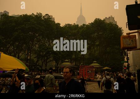 Les piétons dehors pendant la qualité dangereuse de l'air à New York causée par les feux de forêt canadiens. Photo prise à 41st et 6th Avenue, près de Bryant Park, juin Banque D'Images