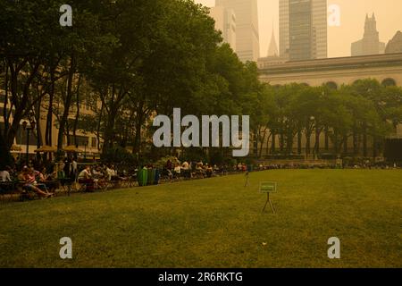 Les gens s'assoient à l'extérieur du Bryant Park pendant la qualité dangereuse de l'air à New York causée par les feux de forêt canadiens. Photo prise aux 44th et 6th Avenue. Banque D'Images