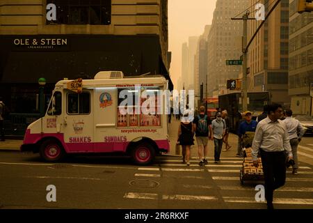 Les piétons dehors pendant la qualité dangereuse de l'air à New York causée par les feux de forêt canadiens. Photo prise aux 40th et 6th avenue, 7 juin 2023. Banque D'Images