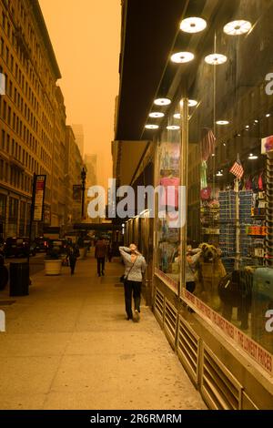 Les piétons dehors pendant la qualité dangereuse de l'air à New York causée par les feux de forêt canadiens. Photo prise aux 36th et 5th avenue, 7 juin 2023. Banque D'Images