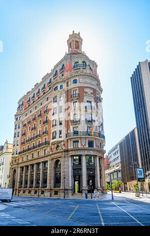 Valence, Espagne - 15 juillet 2022: Un bloc de tour avec des balcons sur un coin de rue entouré par l'architecture de la ville. Les personnes fortuites sont visibles. Banque D'Images