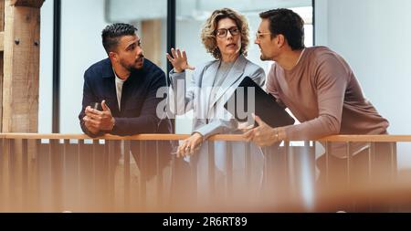 Les designers d'intérieur discutent entre eux dans un bureau. Trois personnes en voyage d'affaires parlent sur un balcon intérieur. Groupe de busine créative Banque D'Images