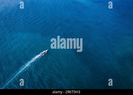 Bateau de pêche traditionnel en bois naviguant dans la mer tropicale bleu profond l'été à la journée ensoleillée Banque D'Images