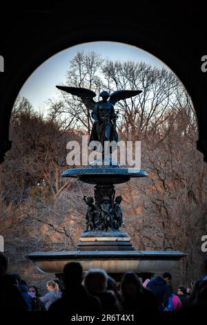 Un coucher de soleil vibrant illumine la majestueuse fontaine de Central Park, avec une foule de personnes rassemblées autour pour admirer la vue imprenable Banque D'Images