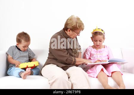 Grand-mère aidant gorl en lisant et jouant avec bébé Banque D'Images