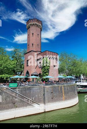 Cologne (Köln, Rheinauhafen, Malakoffturm), Allemagne - 6 juin. 2023: Restaurant de jardin de bière au bord du Rhin avec tour médiévale en pierre Banque D'Images