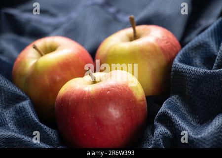 les pommes mûres rouges reposent sur un gros plan en tissu bleu foncé Banque D'Images