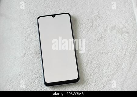 le téléphone avec écran blanc se trouve sur un arrière-plan blanc et doux Banque D'Images