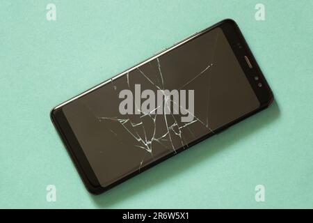 téléphone noir avec écran fissuré sur un arrière-plan isolé Banque D'Images